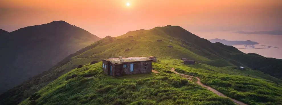 a house on a hill with a sunset in the background - PlanYourTour